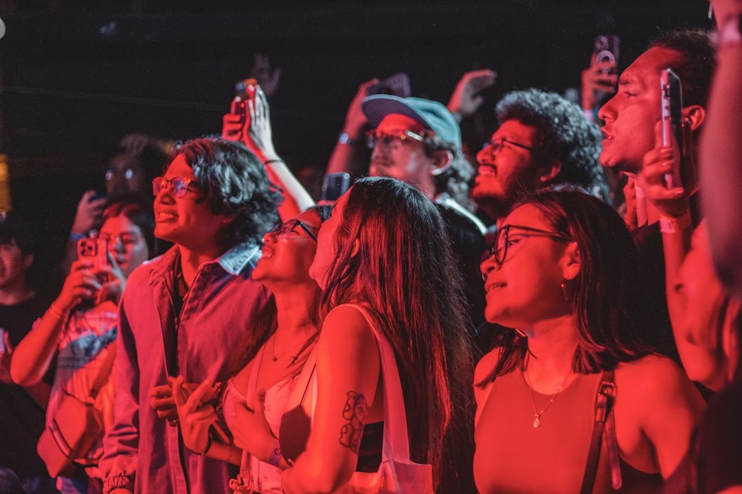 Diverse group of young fans gathered outside a concert venue in the evening